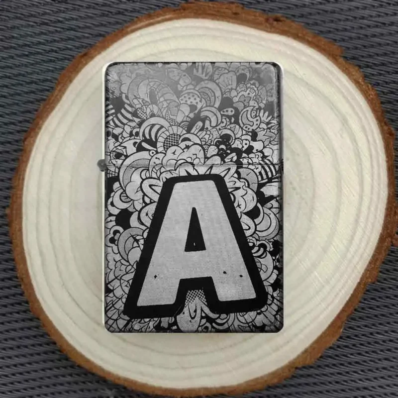 Personalisiertes Feuerzeug mit dem Buchstaben "A" und einem kunstvollen Muster, stimmungsvoll auf einer Holzscheibe arrangiert.
