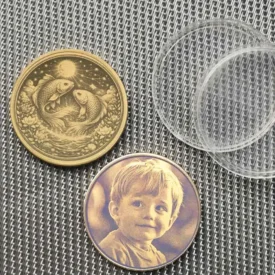 Beispiel der Münze mit optionaler Fotogravur eines Kindes auf der Rückseite statt des Text-Designs, neben der Fische-Vorderseite.