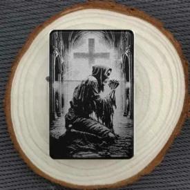 Skull Kirchen Feuerzeug, Schwarz matt mit graviertem betendem Skelett in einer Kathedrale vor einem Kreuz, liegend auf einer Holzscheibe.